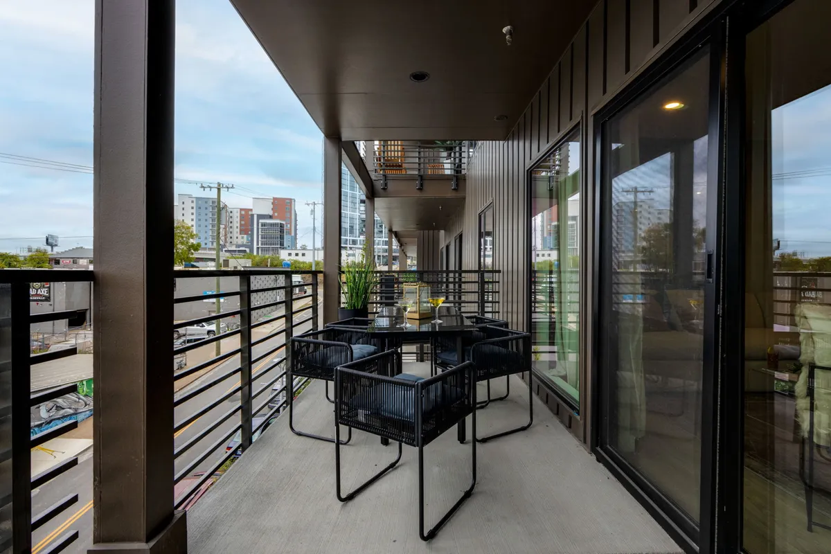A chic outdoor communal seating area framed by the city skyline in the background. Decorative plants and contemporary furnishings create a social, relaxed setting, ideal for gatherings, hanging out with friends, or soaking in the city vibes as day turns to night.