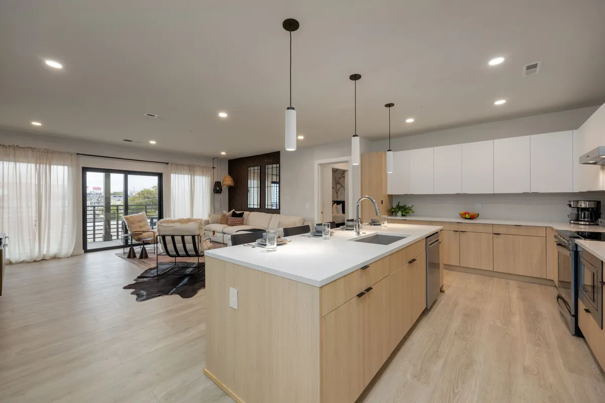 An open-plan layout seamlessly connecting the kitchen island to the living area, with large windows providing plenty of natural light and views. Modern furnishings and a cozy sofa set the stage for entertaining or casual relaxing.